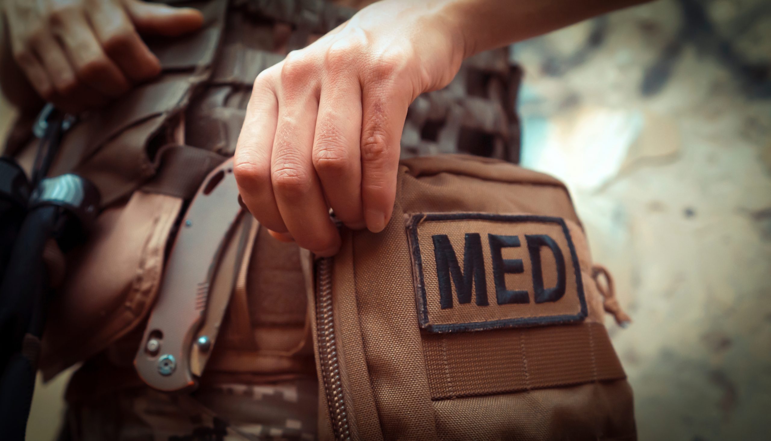 A close up of a military medical personnel reaching into their med bag.